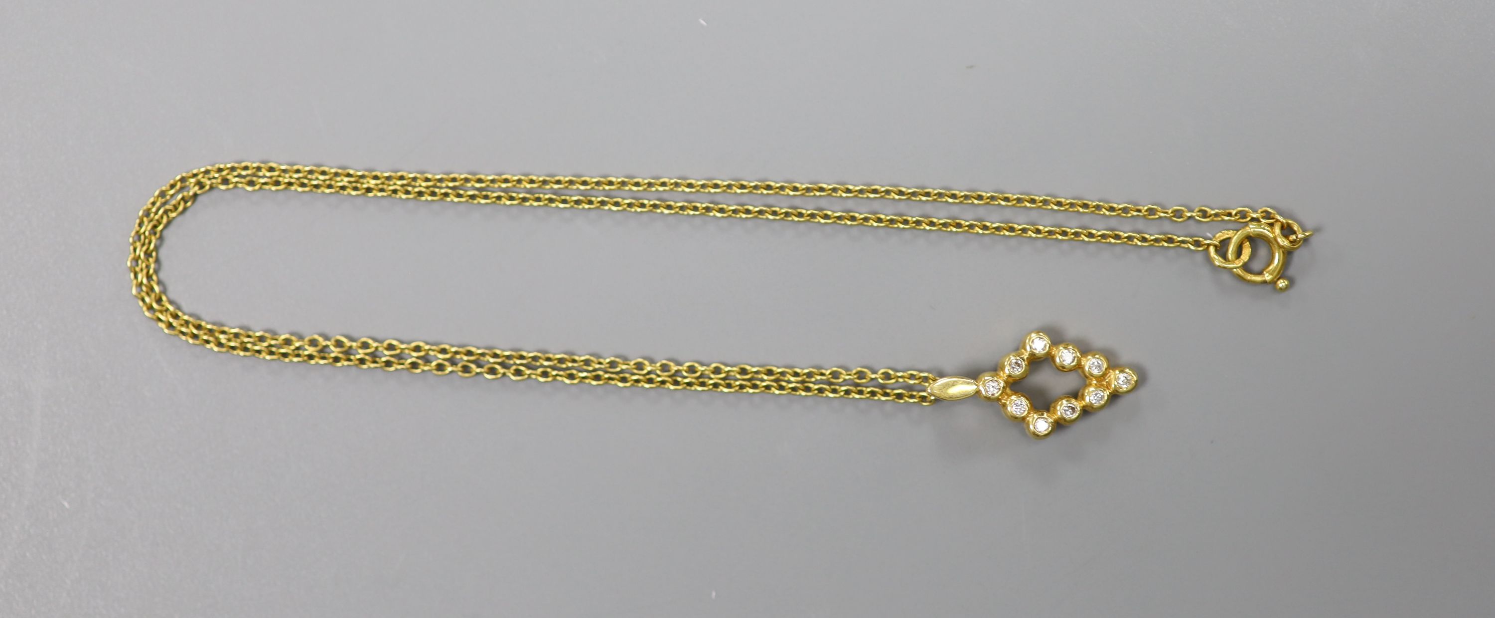 A modern 18ct gold and ten stone diamond chip set pendant, 16mm, on an 18ct chain, 37cm